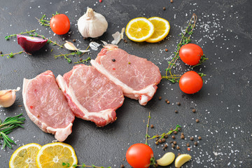 Raw pork meat with spices on dark background