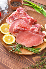 Plate with raw pork meat on wooden background