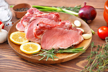 Plate with raw pork meat on wooden background