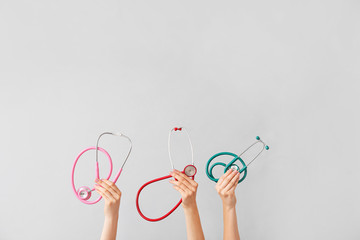 Hands with stethoscopes on grey background