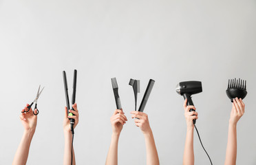 Many hands with hairdresser's supplies on grey background