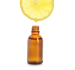 Essential oil dripping from lemon slice into bottle on white background