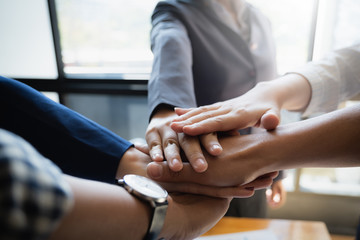 Group of business people putting their hands working together on wooden background in office. group...