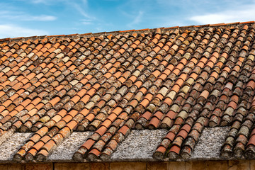 Closeup of a roof with new and old terracotta tiles (clay), on a blue sky with clouds. Veneto, Italy, Europe