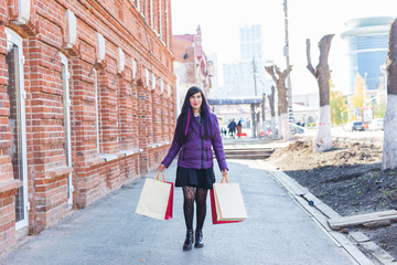 Shopping, consumer and sales concept - Beautiful woman holding many shopping bags on a city street