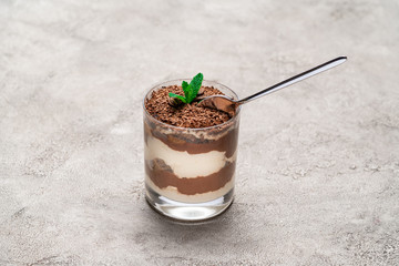 Classic tiramisu dessert in a glass cup on concrete background