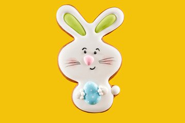 Easter bunny cookie with blue egg over yellow background