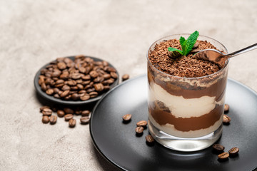 Classic tiramisu dessert in a glass cup on concrete background