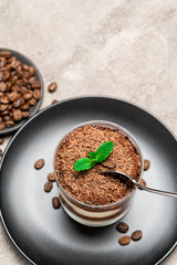 Classic tiramisu dessert in a glass cup on concrete background