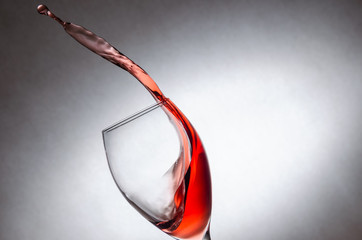 Glass with splashes, drops of red wine on a white background. Freezing liquids in motion. Glass of red wine at an angle with copy space