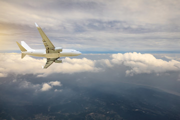 Fototapeta premium Airplane flying at high altitude over green mountains and sky at sunrise
