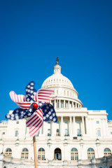 Motion blur view of American flag pinwheel spinning in sunny blue sky in front of the US Capitol building in Washington DC, USA