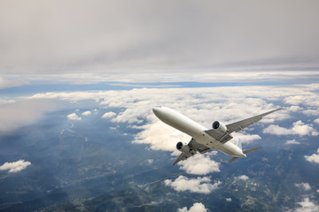 Airplane flying at high altitude over green mountains and sky at sunrise
