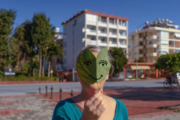  Frau hält Blatt vor Gesicht