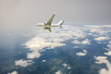 Obraz premium Airplane flying at high altitude over green mountains and sky at sunrise