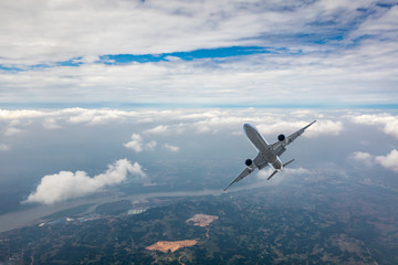 Airplane flying at high altitude over green mountains and sky at sunrise