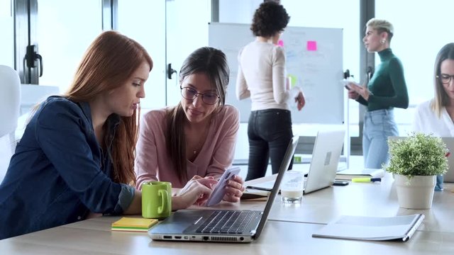 Slow motion shot of businesswomen using smartphone during meeting
