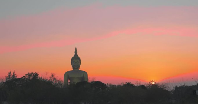 sunset behind the bigest Buddha statue at Wat Muang Ang Thong Thailand.