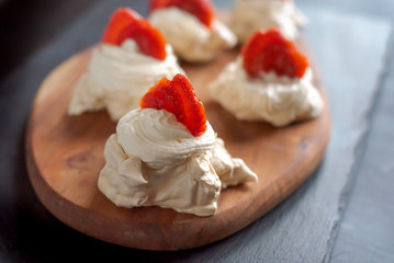 Pavlova dessert, the meringue with strawberries on black.