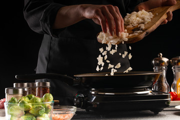 Cooking dishes by the chef, frying onions in a pan. Freezing in motion, against the background of...