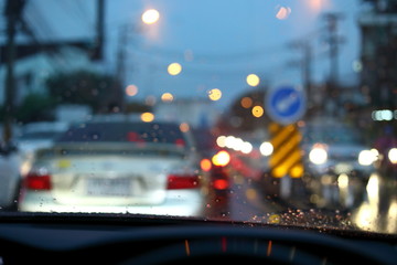 traffic jam on night road city with storm rainy day weather, car driving on street town with water rain drop on windshield outside of bad view