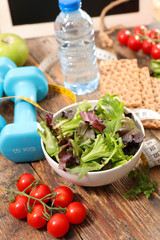 healthy lifestyle with salad, tomato, bottle of water and dumbbell