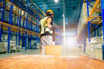 Warehouse worker unloading pallet shipment goods, Interior of storage warehouse,tall shelves...