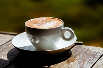 The white cup of coffee on wood table.