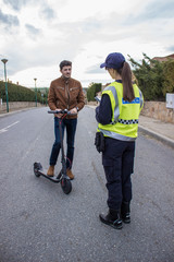 policeman stops a boy on electric scooter