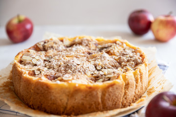 Bratapfelkuchen mit Äpfeln und Mandelblättchen auf hellem weißen Holzgrund
