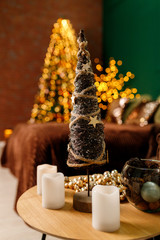 Toy decorative Christmas tree on a table with candles