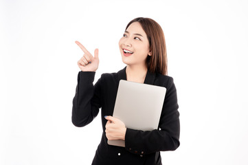 Asian businesswoman with black suit holding a laptop and pointing to present copy space with big smile beaming face in white isolated background.