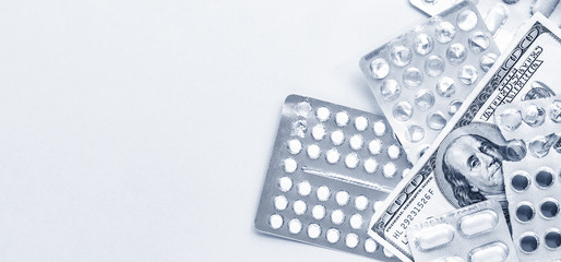 pills in blister with money on a classic blue background, expensive medicine flat lay with copy space