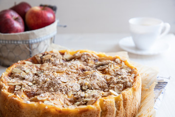 Bratapfelkuchen mit Äpfeln und Mandelblättchen auf hellem weißen Holzgrund