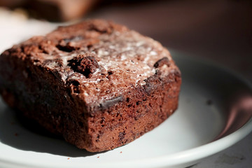 Homemade chocolate cake in white dish and sunlight and space for write wording, unhealthy sweet caused dangerous chronic illness such as diabetes, popular sweet sold in restaurant.