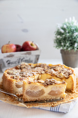 Bratapfelkuchen mit Äpfeln und Mandelblättchen auf hellem weißen Holzgrund