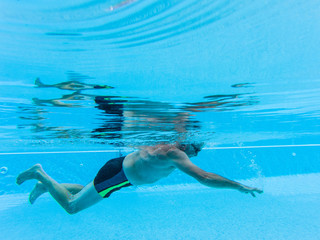 one mature man swimming alone at the pool and doing exercise to e healthy and fitness man - senior inside a swimming pool - underwater view