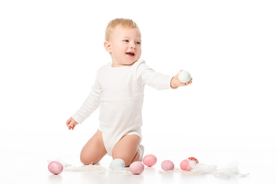 Child next to easter eggs and feathers on white background