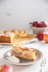 Bratapfelkuchen mit Äpfeln und Mandelblättchen auf hellem weißen Holzgrund