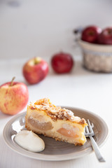 Bratapfelkuchen mit Äpfeln und Mandelblättchen auf hellem weißen Holzgrund