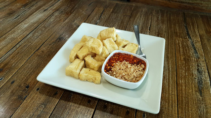 Deep fried crispy tofu in small bite serving with sweet dipping sauce with grounded peanut and chili powder