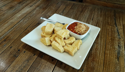 Deep fried crispy tofu in small bite serving with sweet dipping sauce with grounded peanut and chili powder