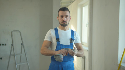 Builder stands and looks at the screwdriver