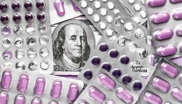 Benjamin Franklin's head with dollar bills looks among blisters with purple pills, medicine flat lay