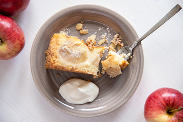 Bratapfelkuchen mit Äpfeln und Mandelblättchen auf hellem weißen Holzgrund