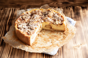 Bratapfelkuchen mit Äpfeln und Mandelblättchen auf dunklen Holzgrund