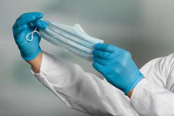 close up of doctor's hand in medical gloves shows medical face mask for protection against infection