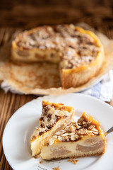 Bratapfelkuchen mit Äpfeln und Mandelblättchen auf dunklen Holzgrund