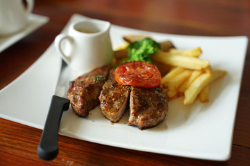 Juicy grounded pork steak with tomato serving with potato chips and black pepper sauce
