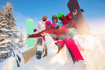 Group of happy friends having fun in winter forest. Snowbarders and skiers group team friendship ski resort sun light